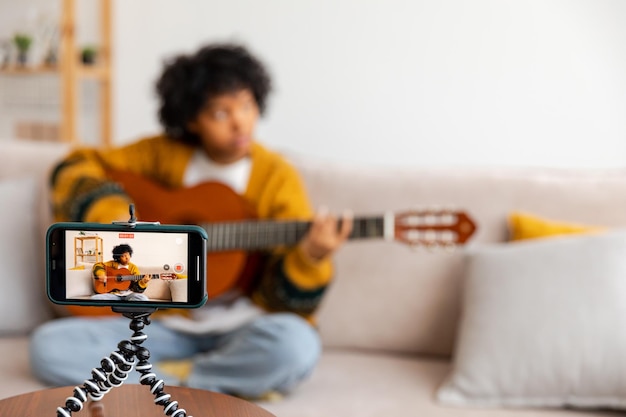 Blogger chitarrista ragazza afroamericana blogger che suona la chitarra parlando con la webcam che registra vlog soci