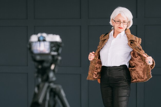 blogger di stilista di moda senior. signora anziana in abito autunnale alla moda ripresa vlog.