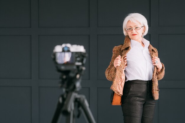 blogger di stilista di moda senior. signora anziana in abito autunnale alla moda ripresa vlog.