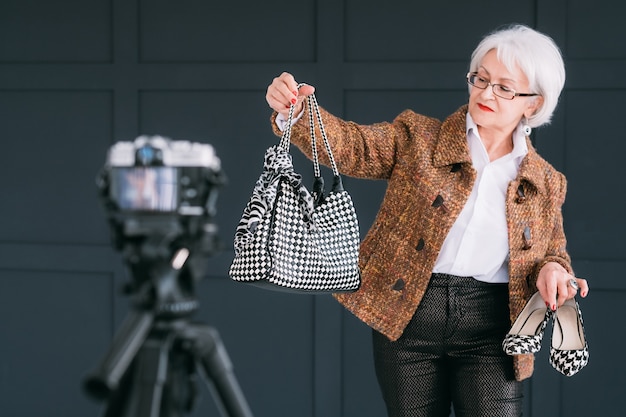 blogger di stilista di moda senior. signora anziana in abito autunnale alla moda ripresa vlog.