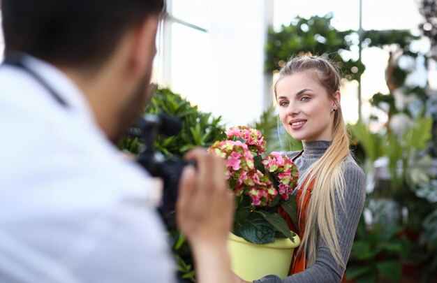 Blogger Donna che registra un fiore rosa con la fotocamera Ragazza fiorista in posa con un fiore di ortensia colorato davanti a un uomo con videocamera Pianta domestica Blog Donna che tiene un vaso di fiori con ortensia gialla