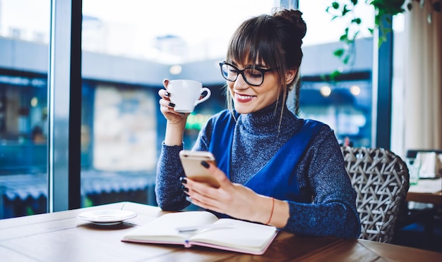 blogger femminile allegra che gode della comunicazione online dal social network collegato al wifi gratuito