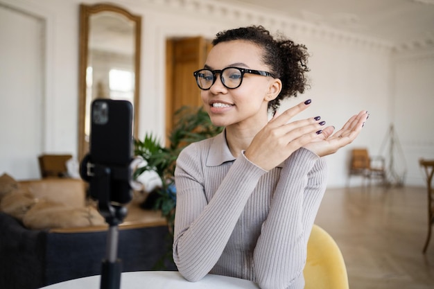 Blogger femminile con occhiali video chat con i colleghi di una società finanziaria in ufficio utilizza il telefono