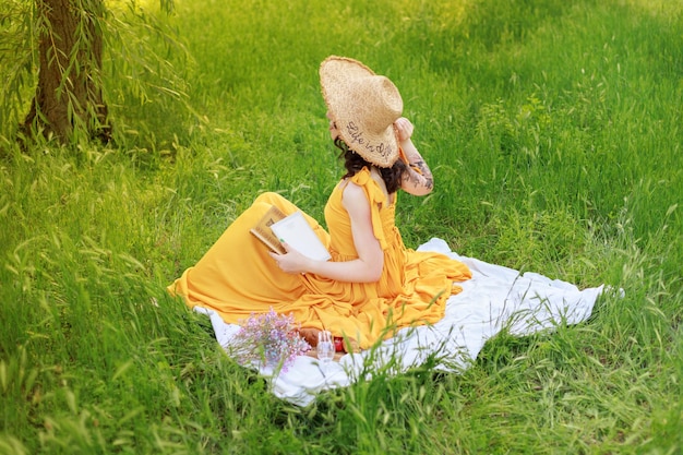 Blogger femminile con un cappello di paglia a un picnic in giardino