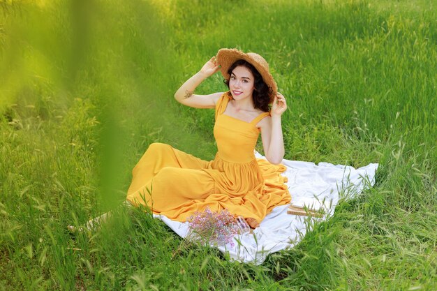 Blogger femminile con un cappello di paglia durante un picnic in giardino in estate