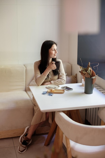 Blogger in un ristorante con una tazza di caffè lavora a distanza