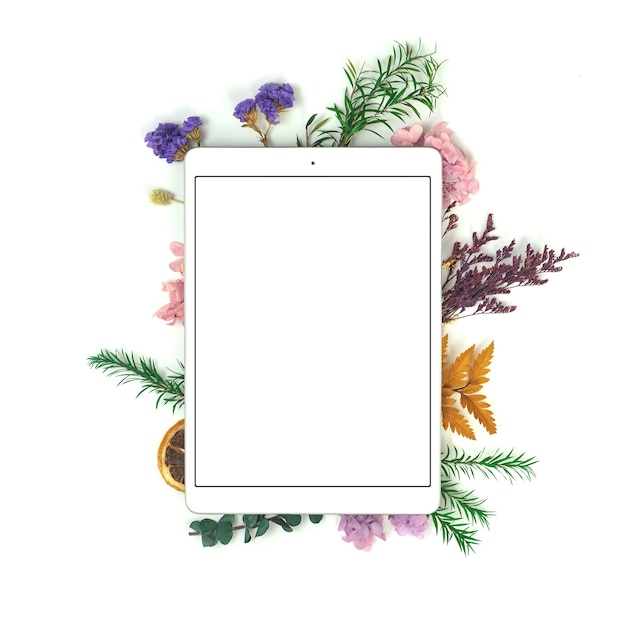 Blogger o spazio di lavoro freelance con tablet pc e fiori secchi floreali, scrivania in stile minimalista, schermo bianco vuoto con foto spazio copia