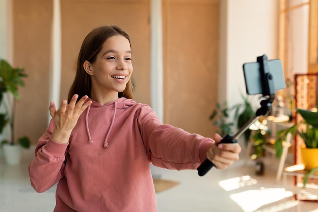 Blogger o vlogger piuttosto famoso per adolescenti in streaming da casa utilizzando il telefono cellulare sul treppiede e parlando con la webcamera