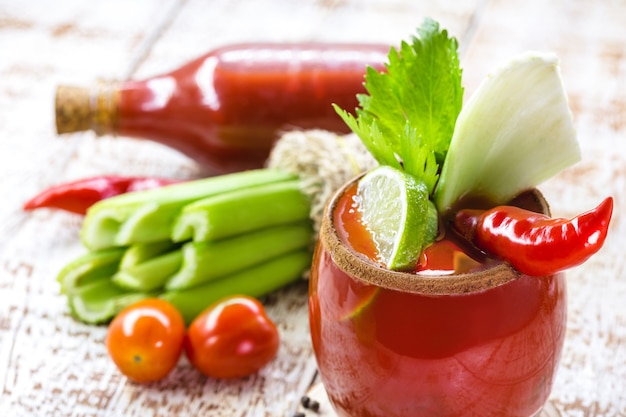 Bloody Mary cocktail e ingredienti, copia spazio, su una superficie di legno bianca