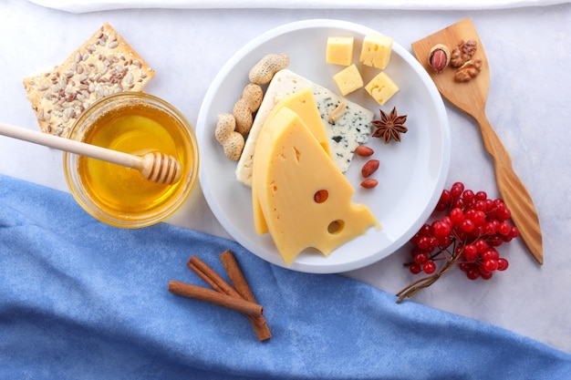 Blue cheese noci bacche e spezie su un piatto bianco Due tipi di formaggio con miele e un tovagliolo whiteblue su sfondo chiaro Primo piano del cibo per la colazione