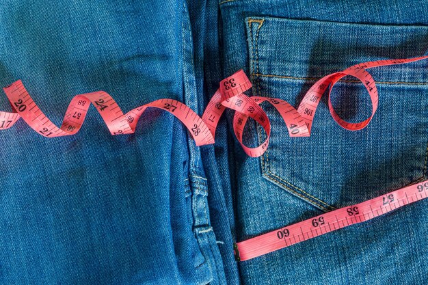 Blue jeans e un primo piano blu del nastro di misurazione Misurazione delle dimensioni Dieta e jeans sani con il rosso