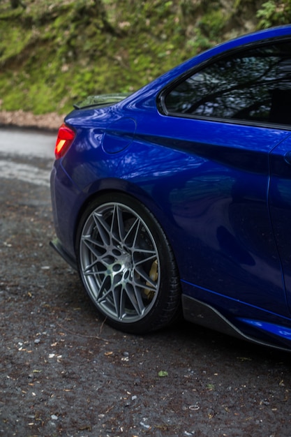 Blue sedan in the vacation zone, back red lights and wheel under the rain