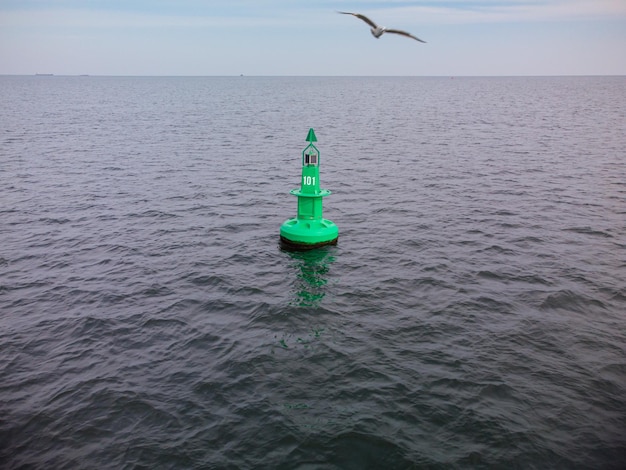 Boa di navigazione verde in mare con le nuvole