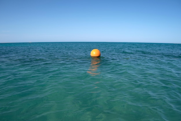 Boa gialla che galleggia sulla superficie del mare come indicatore per la limitazione del nuoto in acque profonde al resort tropicale. Concetto di sicurezza della vita umana.