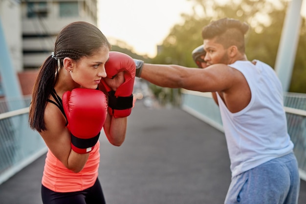 Bob and weave Inquadratura di una giovane coppia che si allena con kickboxing all'aperto su un ponte