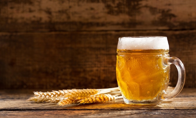 Boccale di birra con spighe di grano sulla tavola di legno