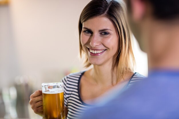 Boccale di birra sorridente della tenuta della giovane donna