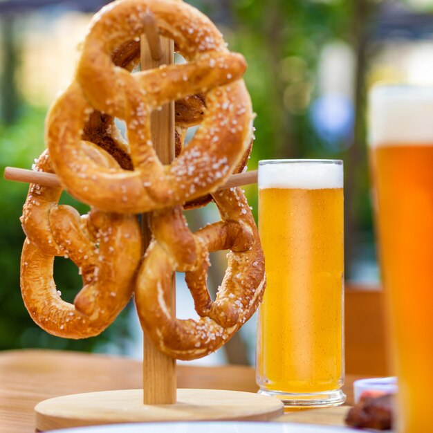 Boccali da birra con pretzel sul tavolo, sfondo verde