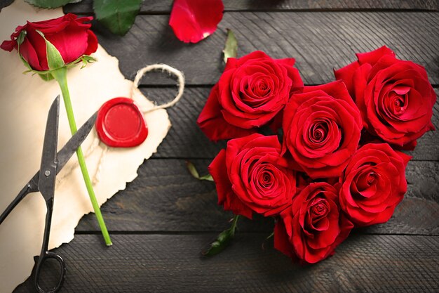 Boccioli di rose rosse fresche a forma di cuore con scheda presente in bianco sulla tavola di legno