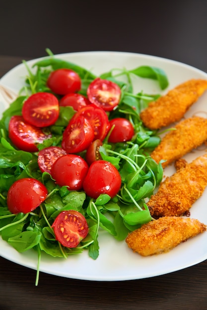 Bocconcini di pollo serviti con rucola e pomodorini