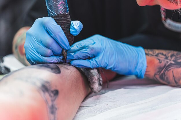 Body art concept close-up di uno studio di tatuaggio professionista sterile con due mani in guanti blu