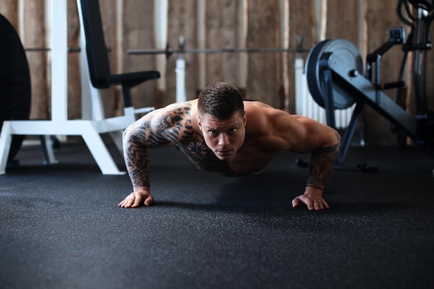 Bodybuilder dedicato che esegue flessioni nella foto della palestra con un copyspace