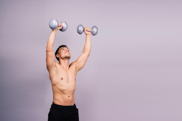 Bodybuilder senza camicia che mostra il suo grande corpo e tiene il manubrio