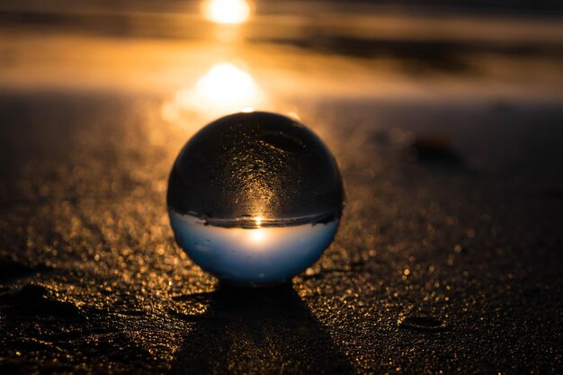 Bola di cristallo sulla sabbia sulla spiaggia durante il tramonto