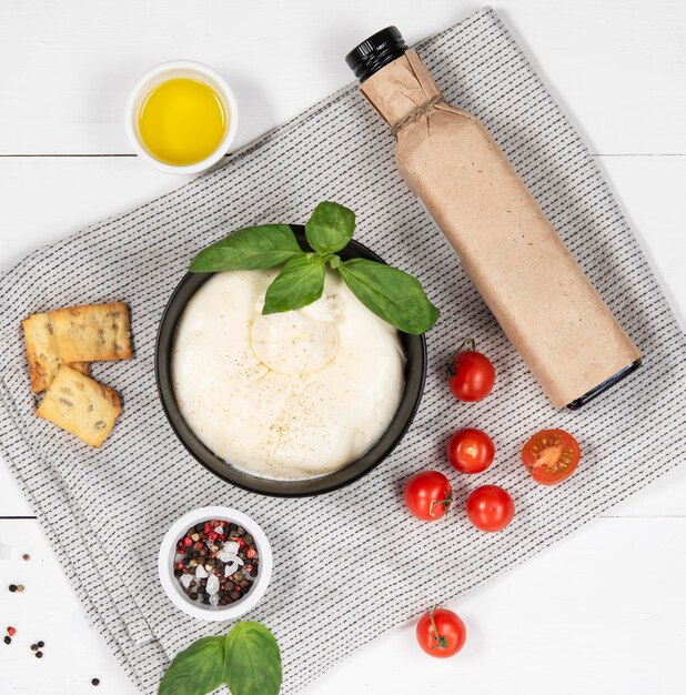 Bolla di formaggio bianco morbido fresco di mozzarella e crema burrata in una ciotola con pomodori freschi, basilico e olio d'oliva