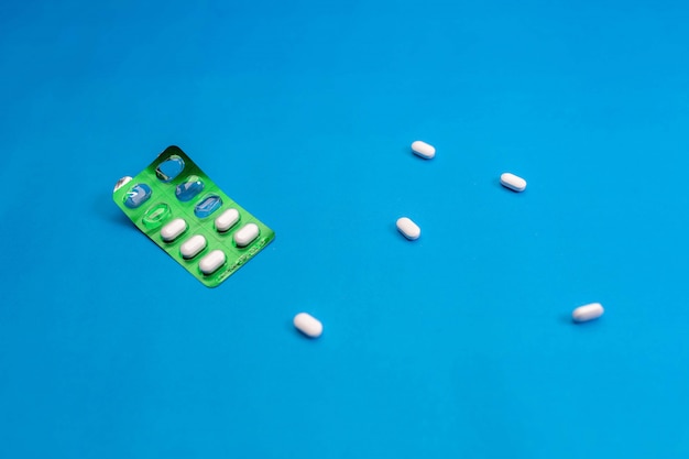 Bolla verde per le pillole con le compresse sparse su un blu. Salute. Uno stile di vita sano .