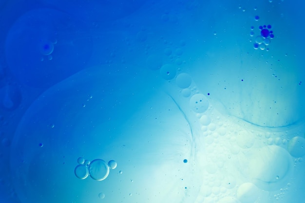 Bolle d'olio vicino cerchi di acqua macro astratto sfondo azzurro