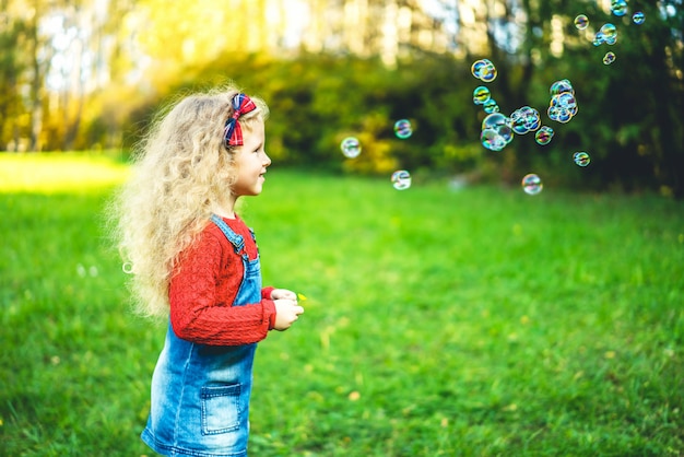 Bolle di salto della bambina graziosa nel parco.