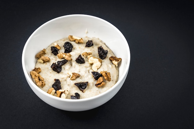 Bollimmo il latte con l'avena e aggiungemmo le prugne e le noci. Ricetta di farina d'avena con noci, prugne secche, cannella e zucchero.