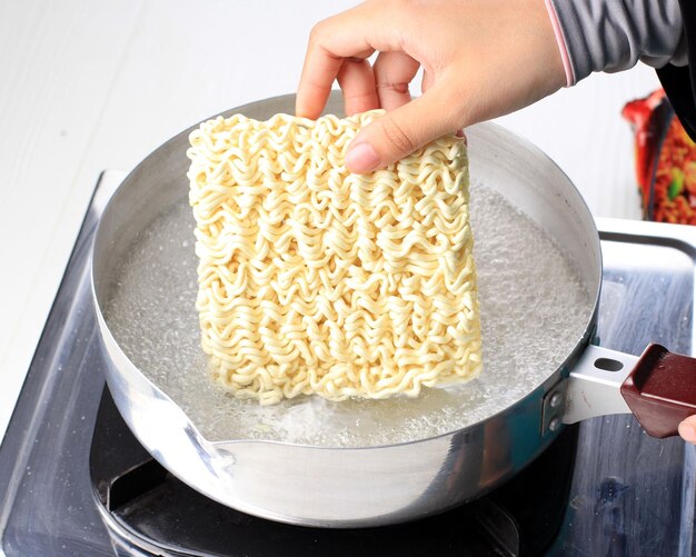 Bollire i noodle istantanei coreani con il rameyun piccante in padella. Aggiungere i noodle nella padella