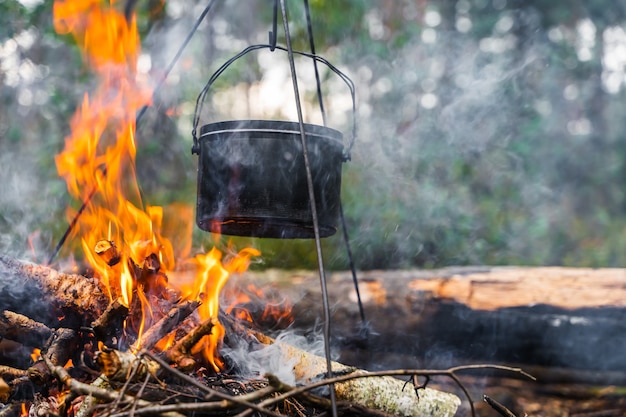 Bollitore appeso sopra il fuoco. Cottura del cibo a fuoco in natura. Viaggiare, concetto di turismo. Foto d'archivio