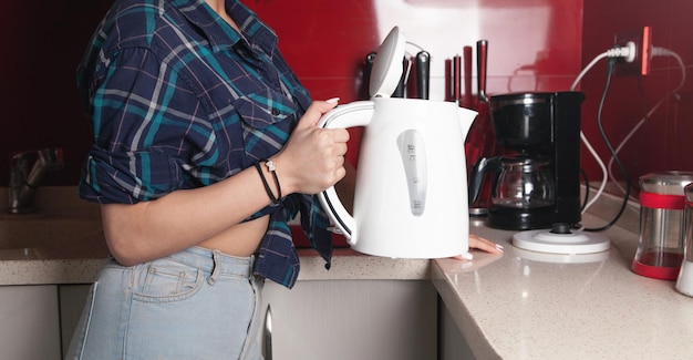 Bollitore della holding della donna. Preparare una bevanda calda