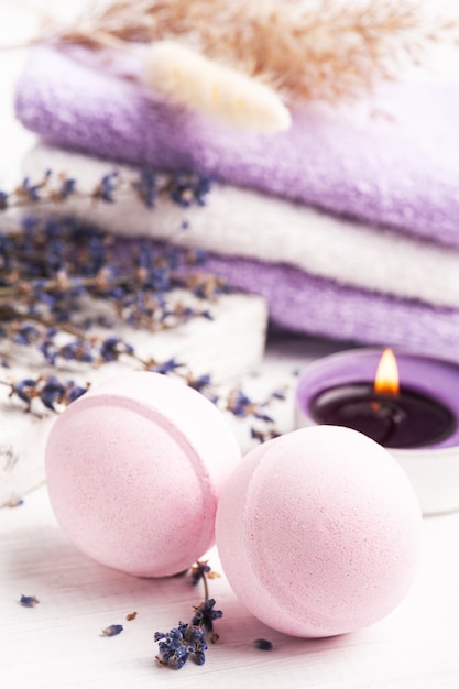 Bombe da bagno aromatiche rosa nella composizione spa con fiori di lavanda secca e asciugamani. Disposizione di aromaterapia, natura morta zen con candele accese