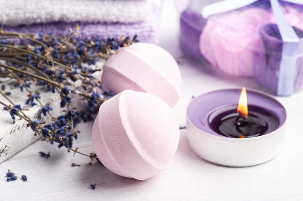 Bombe da bagno aromatiche rosa nella composizione spa con fiori di lavanda secca e asciugamani. Disposizione di aromaterapia, natura morta zen con candele accese