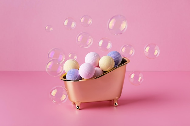 Bombole di bagno di sale in una vasca da bagno con bolle di sapone su sfondo rosa Idea creativa di bombe da bagno cura del corpo trattamento di bellezza