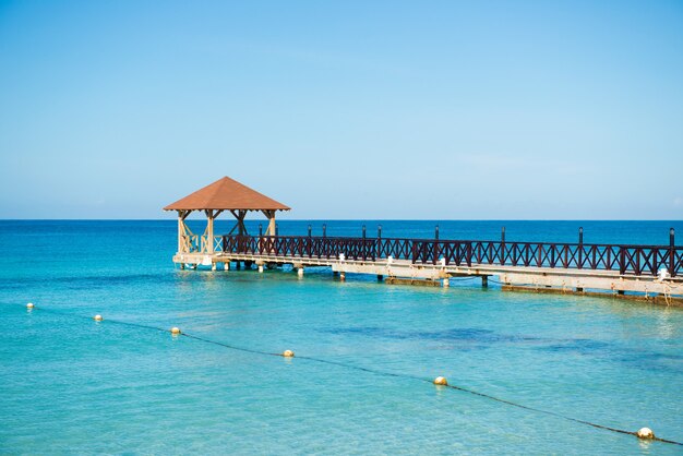 Bonaccia. Molo in legno, mare turchese, orizzonte blu e cielo limpido e senza nuvole.