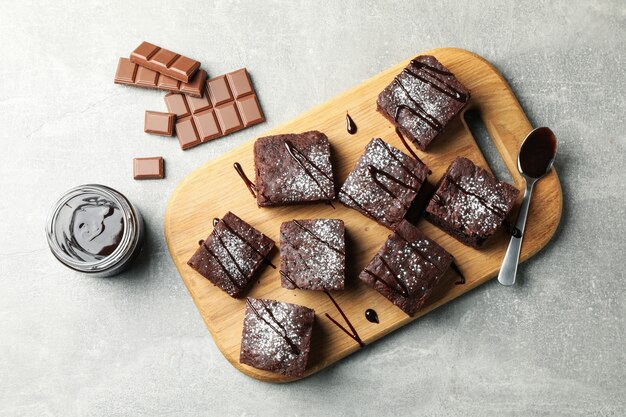 Bordo con fette di torta al cioccolato e cioccolato su grigio, vista dall'alto