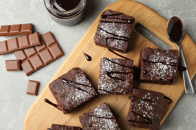 Bordo con fette di torta al cioccolato e cioccolato su grigio, vista dall'alto