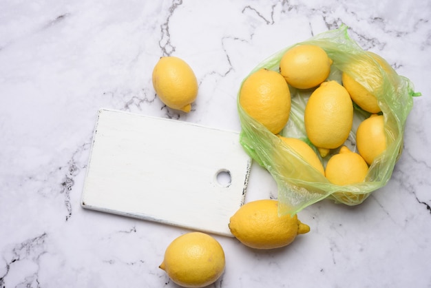 Bordo di legno bianco di limoni gialli maturi, ingrediente per limonata, vista dall'alto