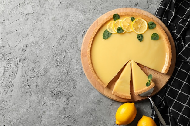 Bordo di legno con la crostata al limone su gray con l'asciugamano, vista superiore