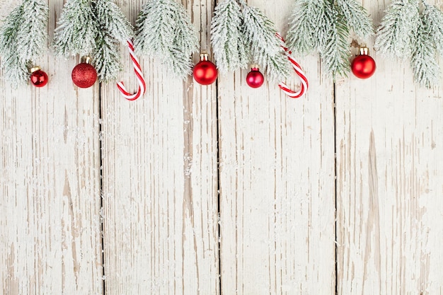 Bordo di Natale su carta di sfondo in legno bianco Palline di bacche di agrifoglio rosso e ramo di abete verde Minimal Xmas flat lay top view su struttura di legno con spazio per la copia