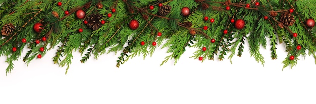 Bordo di ramoscelli verdi con decorazioni natalizie su bianco