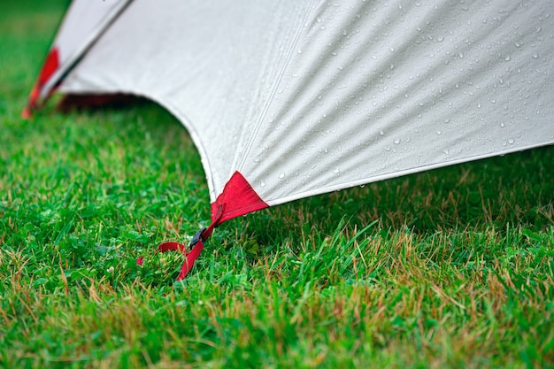 Bordo di una tenda turistica tesa con corde sull'erba verde all'aperto in estate