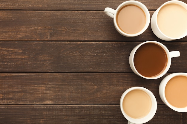 Bordo di vari tipi di caffè in tazze di diverse dimensioni su tavola in legno rustico, vista dall'alto, spazio copia