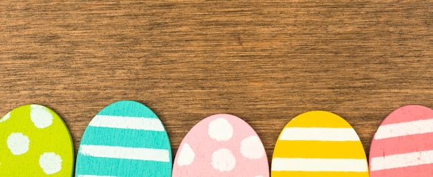 Bordo inferiore del banner colorato delle uova di Pasqua, vecchio fondo di legno rustico, design piatto, vista dall'alto con foto dello spazio della copia