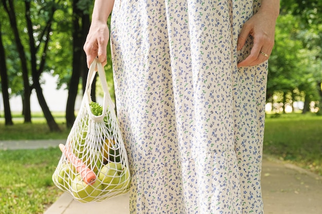 Borsa a rete lavorata a maglia con frutta e verdura nelle mani di una donna